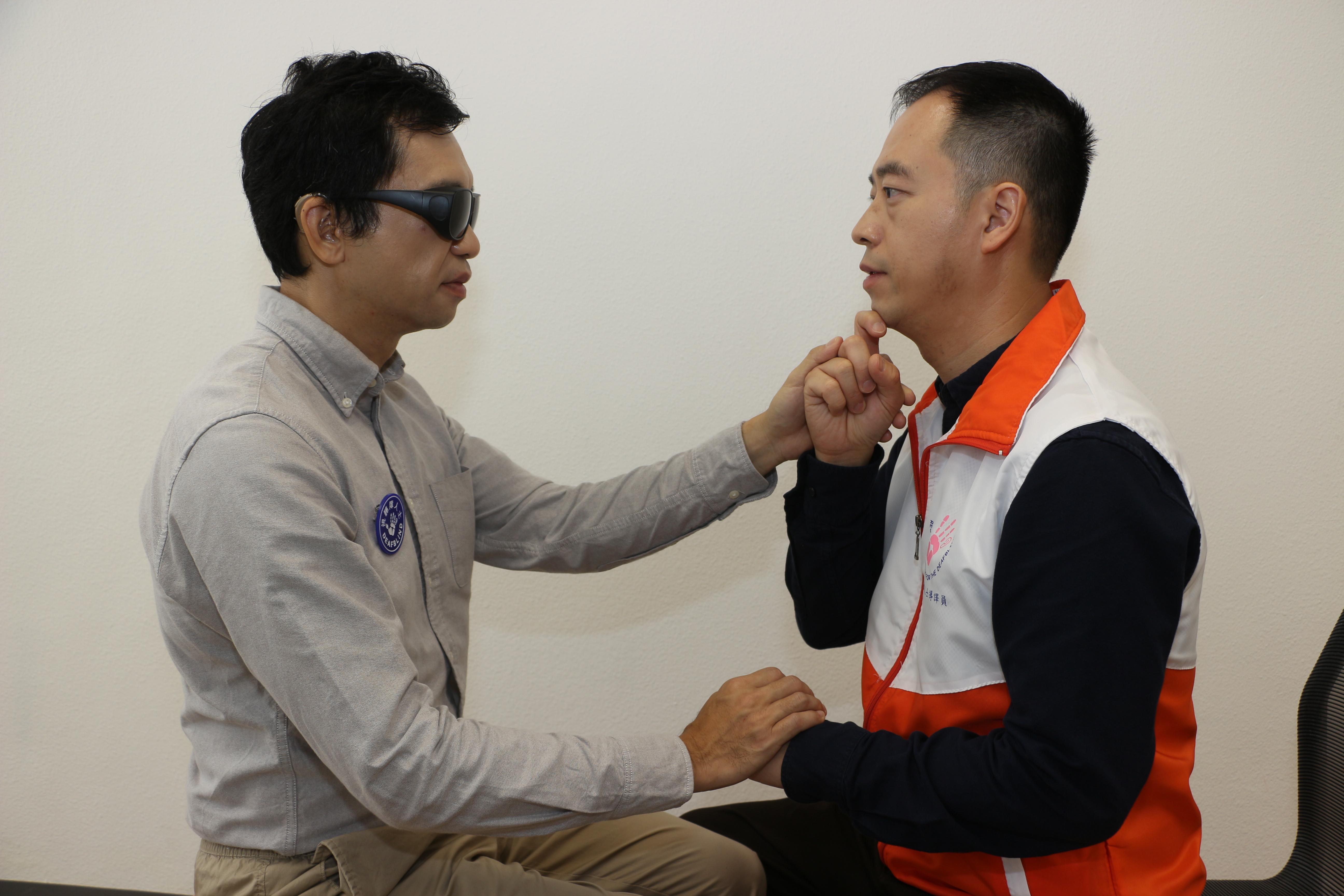 导译员运用触感手语与视听障人士沟通。